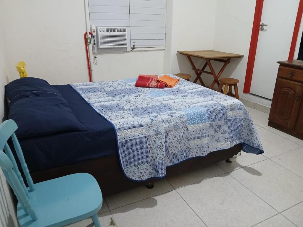 a bedroom with a bed with a blue blanket and a blue chair at Estalagem Triplex Vermelho in Vitória