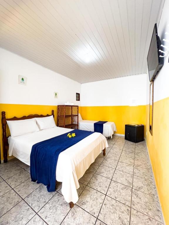 a bedroom with two beds and a flat screen tv at Pousada Sol E Mar in Morro de São Paulo