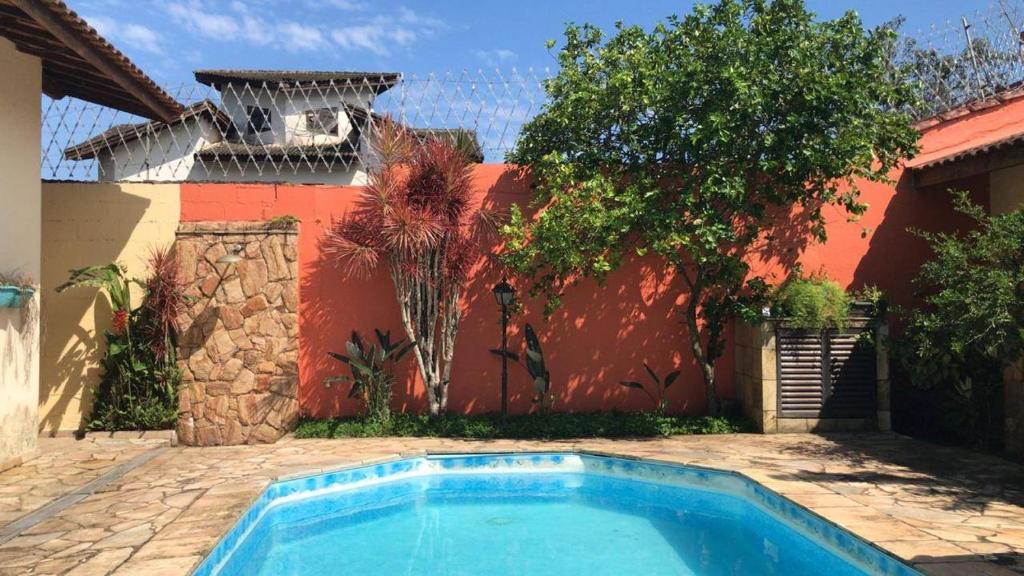 a swimming pool in front of a red house at Pousada Allmar in Bertioga