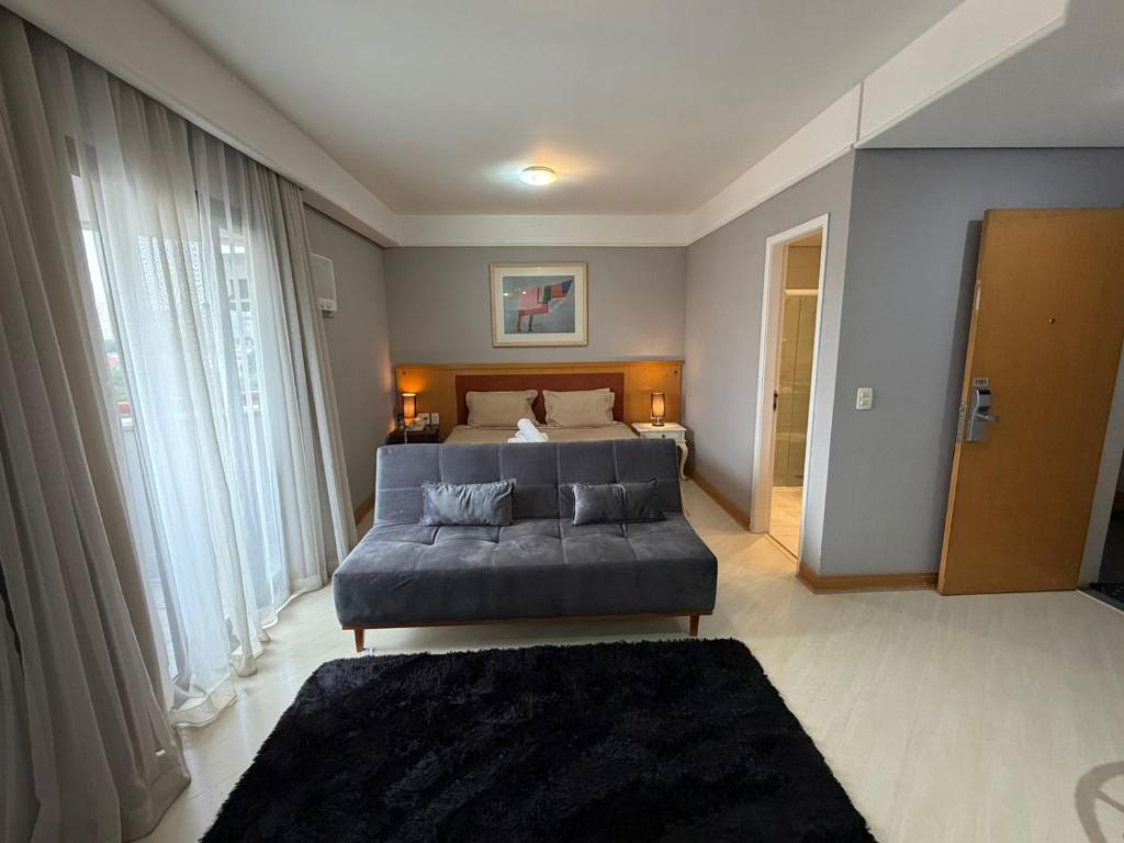 a bedroom with a bed and a blue couch at Hotel Flat Biena Parque Ibirapuera 1101 incluso estacionamento in São Paulo