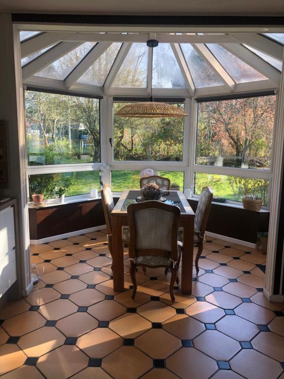 a dining room with a glass conservatory with a table and chairs at Woodune in Neufchâtel-Hardelot