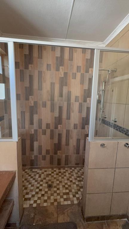 a bathroom with a shower and a tiled wall at Unit 7-9 at Homely Escapes in Phalaborwa