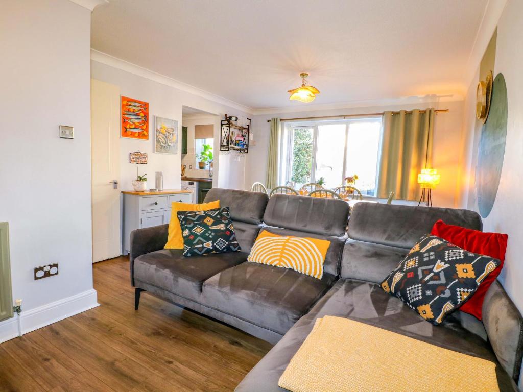 a living room with a brown leather couch with colorful pillows at Farnham Park Apartment in Farnham