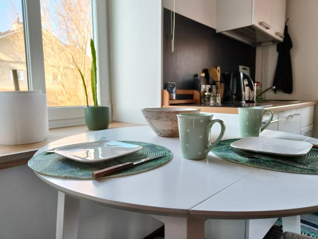 a white table in a kitchen with plates and cups at Tartu tänava külaliskorter in Viljandi