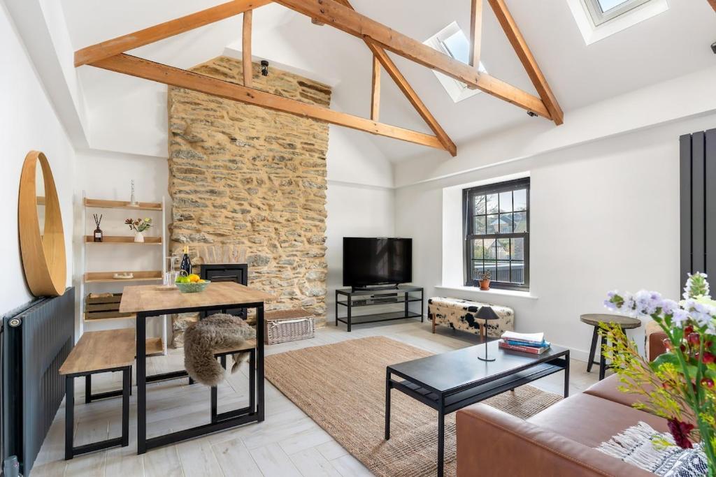 a living room with a stone wall and a table at Cosy Nook at Jam Jar Kitchen in Crantock
