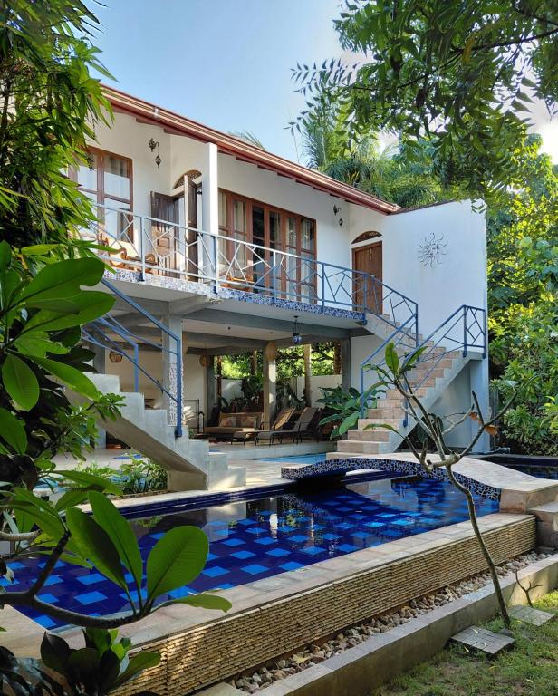 a villa with a swimming pool in front of a house at Villa Mosaic in Tangalle