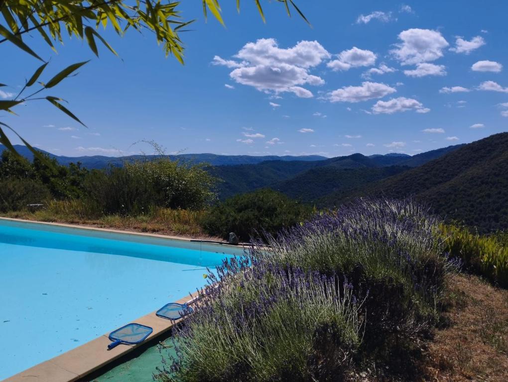 a swimming pool with mountains in the background at Mas de la Petite Occitane - Cévennes sud in Saint-André-de-Majencoules