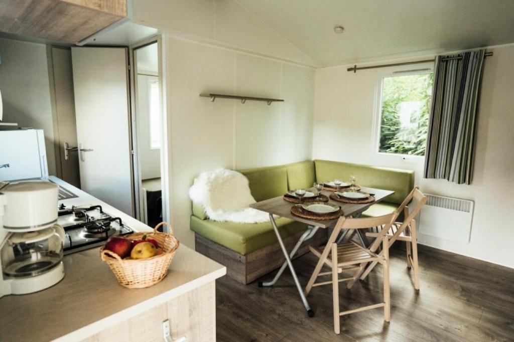 a small kitchen with a table and a couch in a room at Camping Kerscolper - Mobil home 3 pièces 4/6 personnes + TV MAE-9591 in Fouesnant