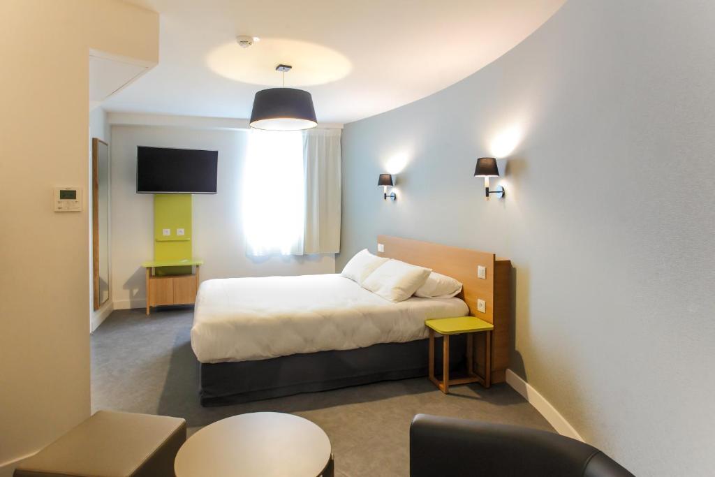 een hotelkamer met een bed en een stoel bij Hotel Reseda in Bagnolet