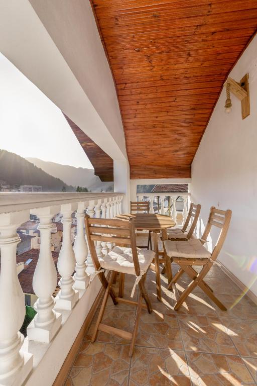 a balcony with a wooden ceiling and wooden tables and chairs at Кума Лиса in Devin