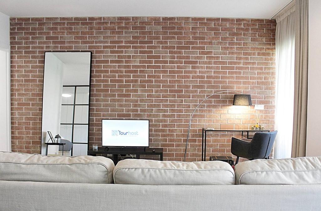 a living room with a couch and a brick wall at Arrábida Luxury Studio in Vila Nova de Gaia