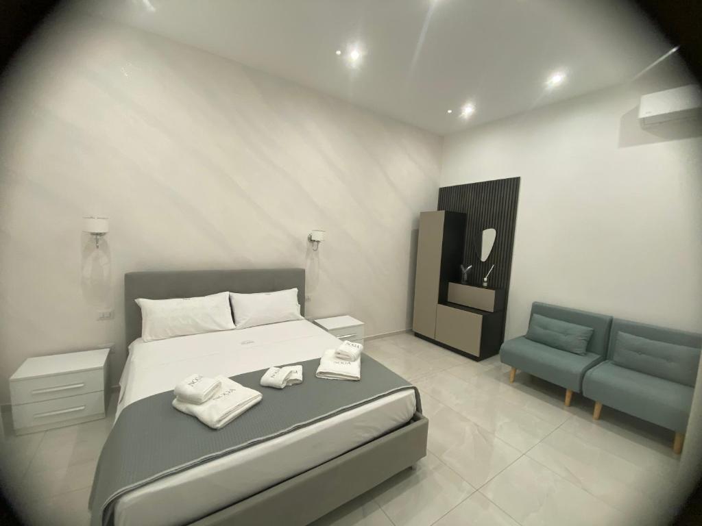 a bedroom with a bed and a blue chair at NOGA rooms in Porto Cesareo