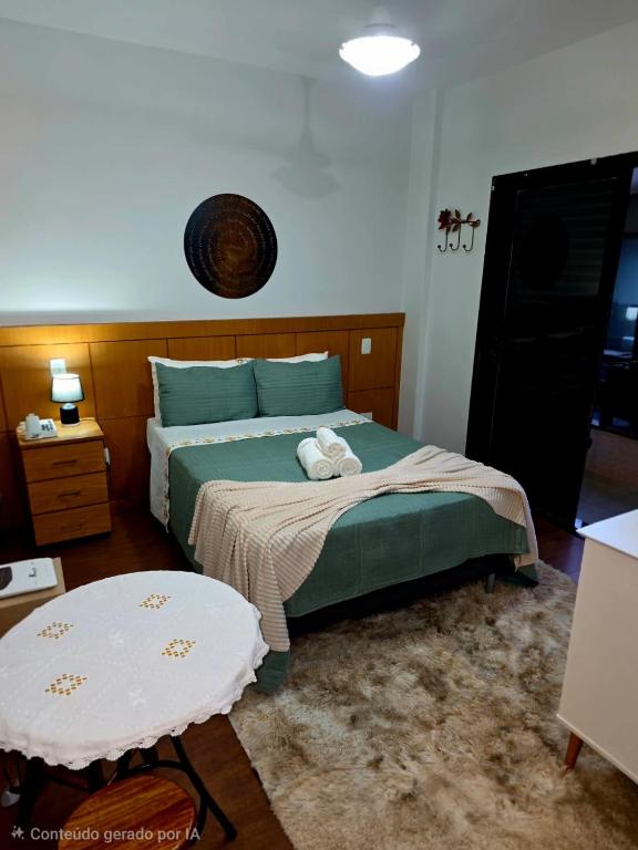 a bedroom with a green bed and a table at Flat 108B com lazer próx ao centro in Serra Negra