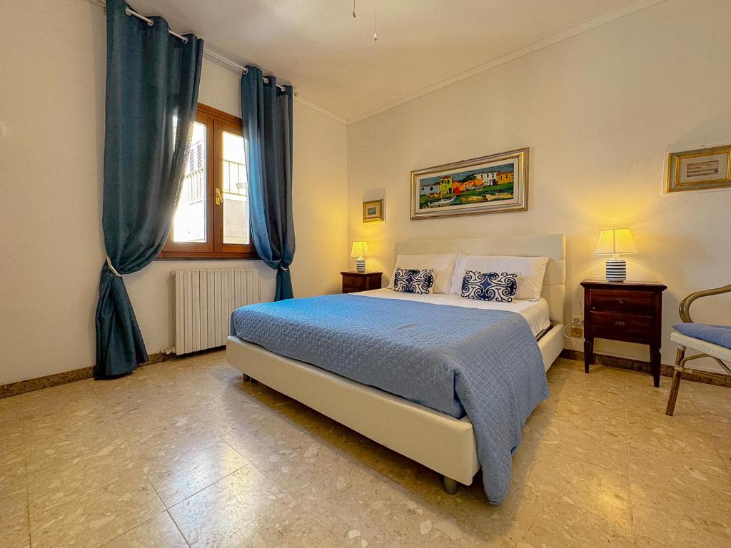 a bedroom with a bed and a window with blue curtains at 49 Sea Rooms - Guesthouse by Host Hero in Stintino