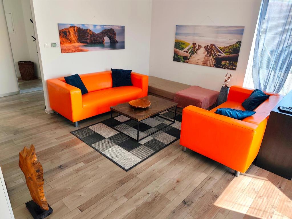 a living room with two orange chairs and a table at Comfort Apartment for 6 & Loggia & Free Parking in Žilina