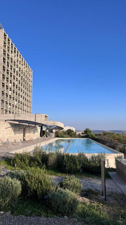 a swimming pool in front of a large building at Garden views in Juriquilla