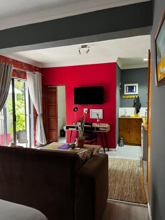 a living room with a couch and a red wall at Bird Song in Roodepoort