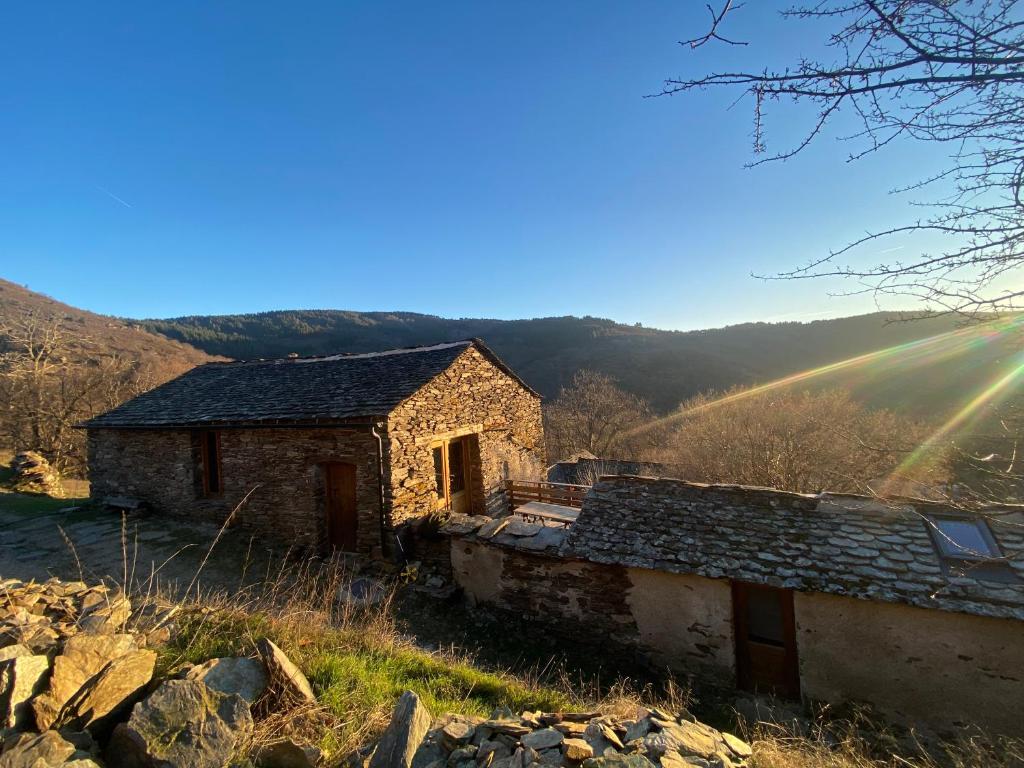 an old stone house on a hill with a rainbow at La grange de Jean et Claude in Barre-des-Cévennes