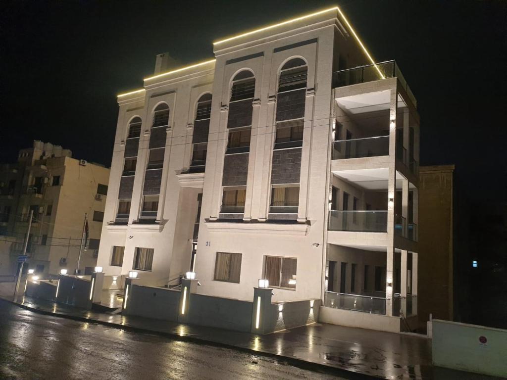 a white building at night with lights on it at Masaken Hotel Apartment in Amman