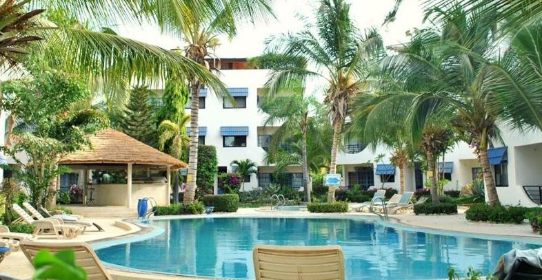a large swimming pool with chairs and palm trees at Appartement à Natangue 1 in Saly Portudal