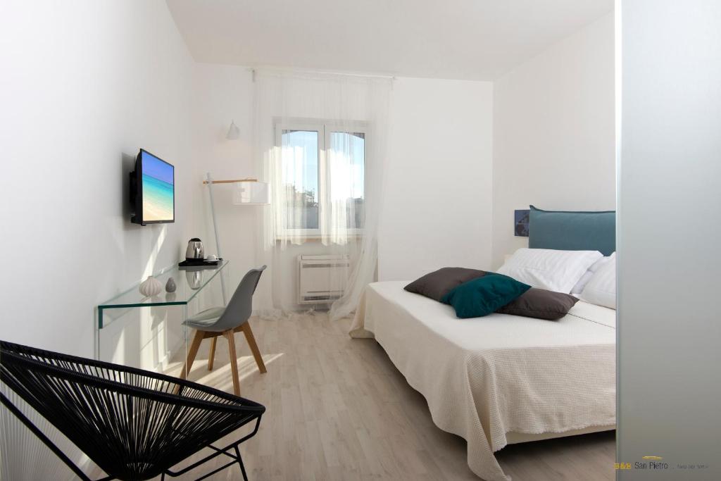 Habitación blanca con cama y escritorio en B&B San Pietro, en Isquia