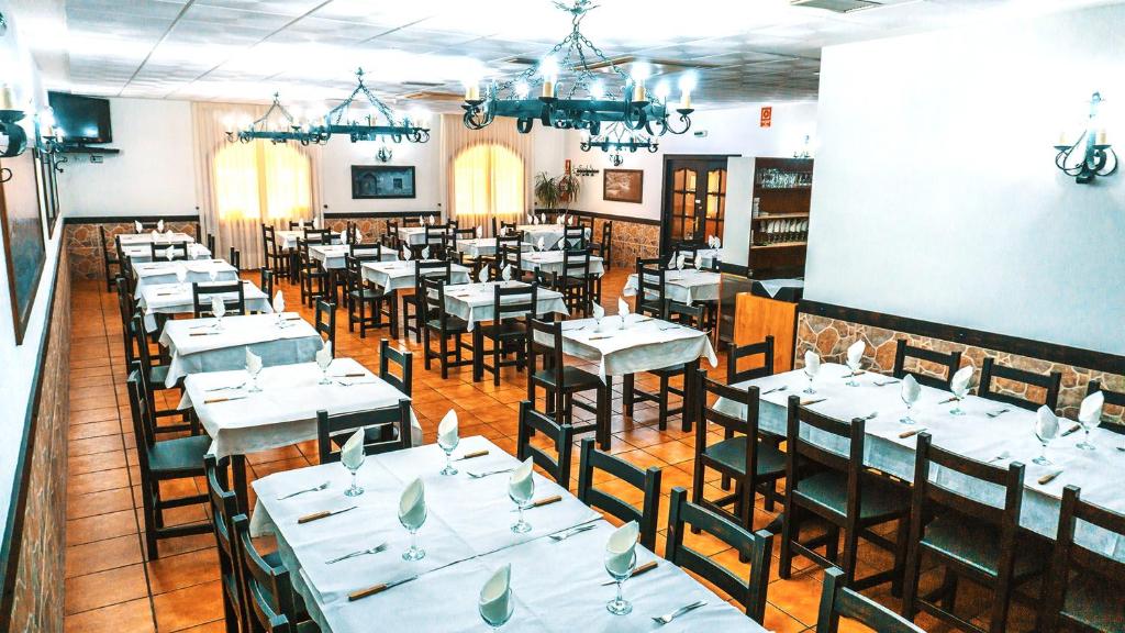 uma sala de jantar com mesas e cadeiras brancas em Hotel Restaurante Caracho em Corella