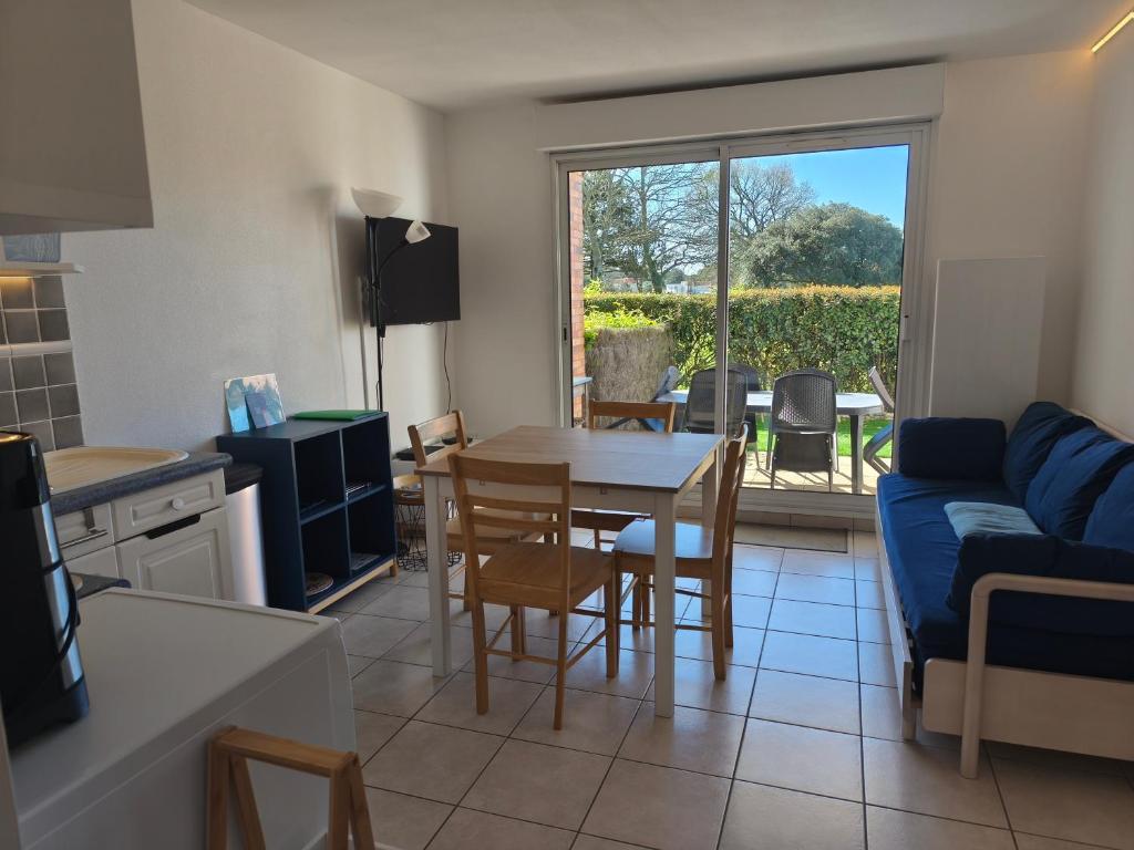 a kitchen and living room with a table and a blue couch at T2 L'orée du Golf labellisé 3 étoiles - Terasse et Parking in Pornic