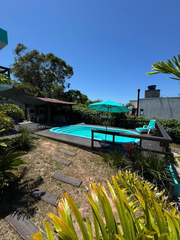 a swimming pool with a table and an umbrella at Pousada Mahara - Praia do Rosa in Imbituba