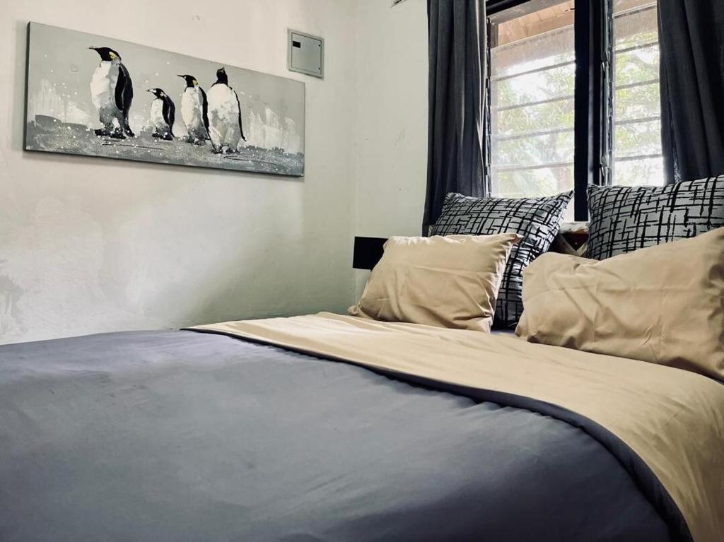 a bedroom with a bed with penguins on the wall at Ntinti Stays Cottage in Ndola
