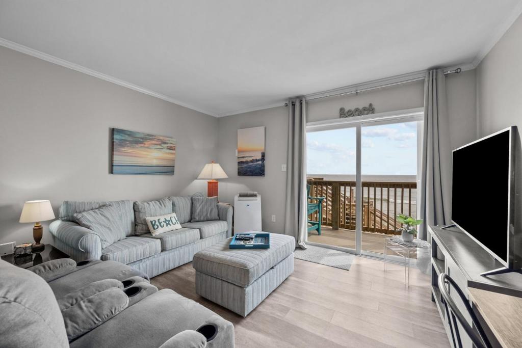 a living room with a couch and a television at Feel the Sea Breezes in North Topsail Beach