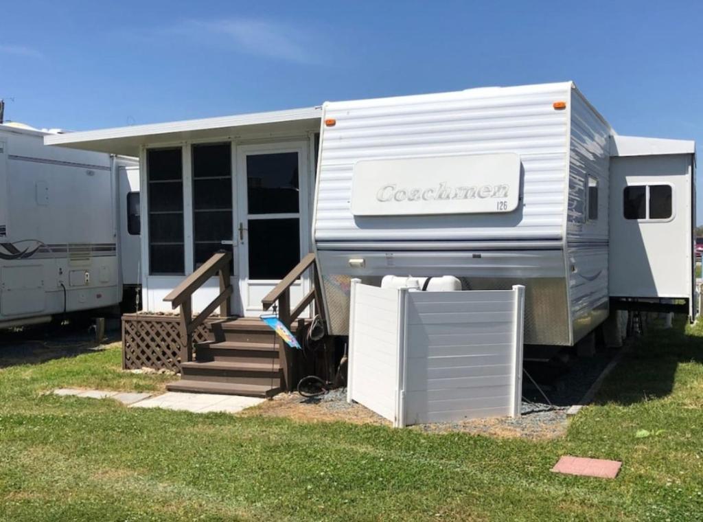 an rv parked in a field with its door open at Cozy Camper NTB in North Topsail Beach