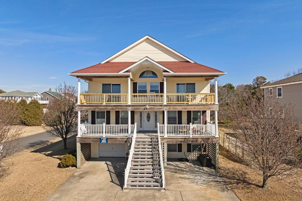 a large house with a porch and a deck at Sounds Like A Plan in Kill Devil Hills