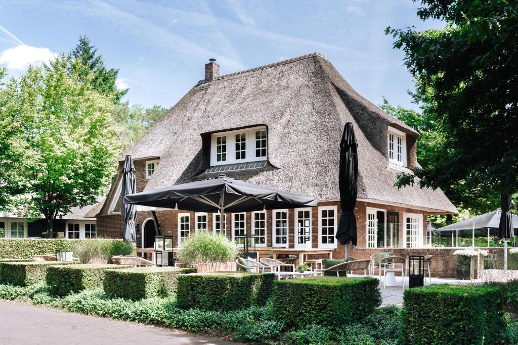 a thatched house with an umbrella in front of it at De Swarte Ruijter in Holten