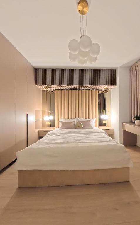 a bedroom with a large white bed and a chandelier at LUAME Residence , langa Arena Mall, aproape de centru in Bacău
