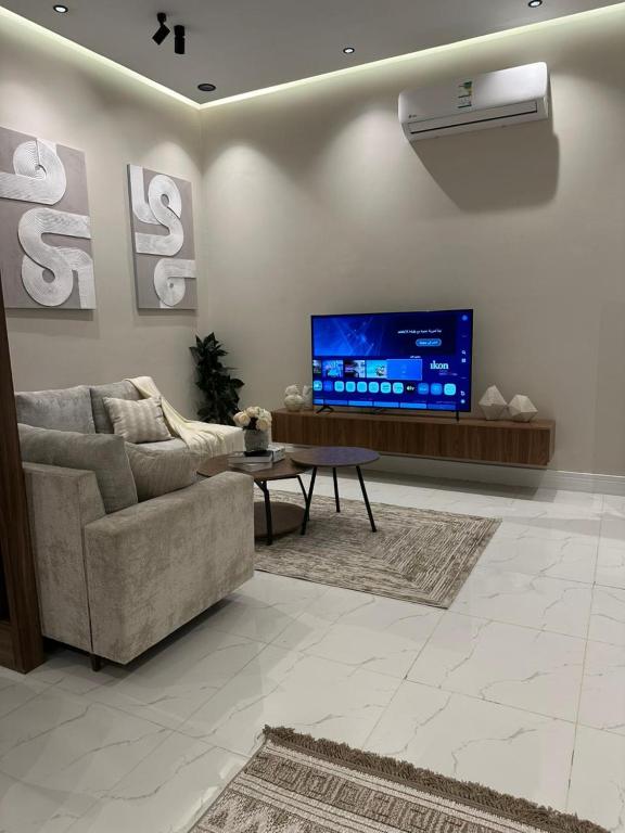a living room with a couch and a tv at شقة اند هوم in Hail