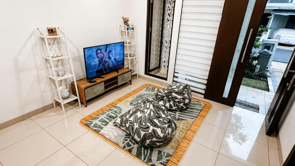a living room with a television and a rug at Lee Simple House - Summarecon Bandung in Tegallebu