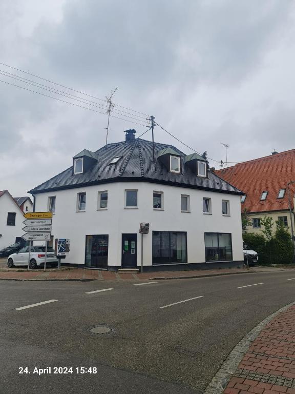 a white building with a black roof on a street at My Pension City Stadtbergen Augsburg in Stadtbergen