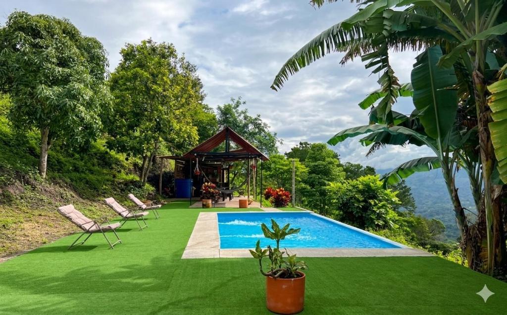 a pool with a gazebo and chairs on a green lawn at Finca Bellavista in Villeta