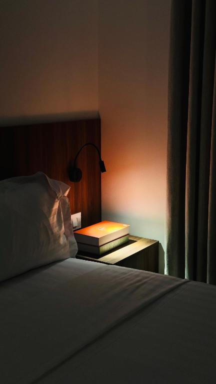 a bed with a lamp and a book on a night stand at الزاوية للشقق الفندقية in Medina