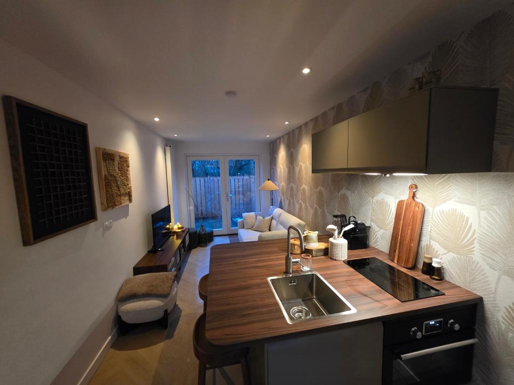 a kitchen with a sink and a living room at Riekje in Lage Zwaluwe