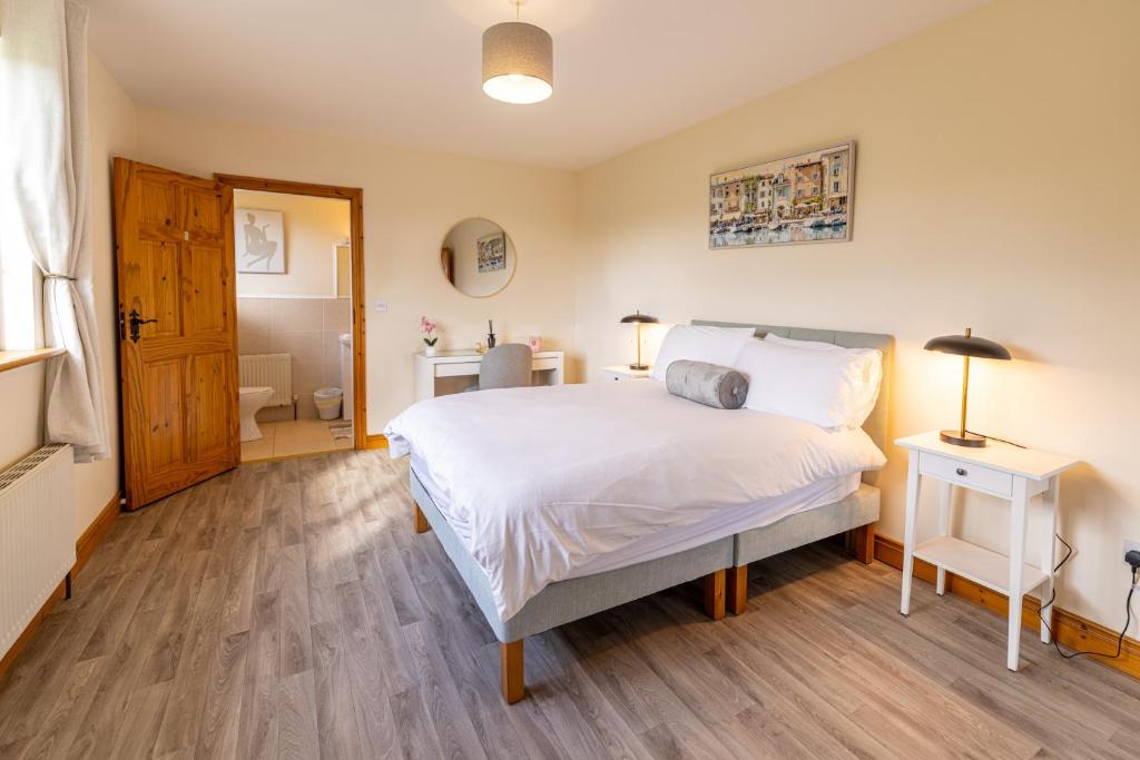 a bedroom with a white bed and a bathroom at Hillside House - Rose Cottage in Ballinamuck