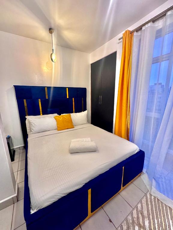 a bedroom with a blue and yellow bed with a window at Sunstone Studio- Ngong Rd Near Junction Mall in Nairobi