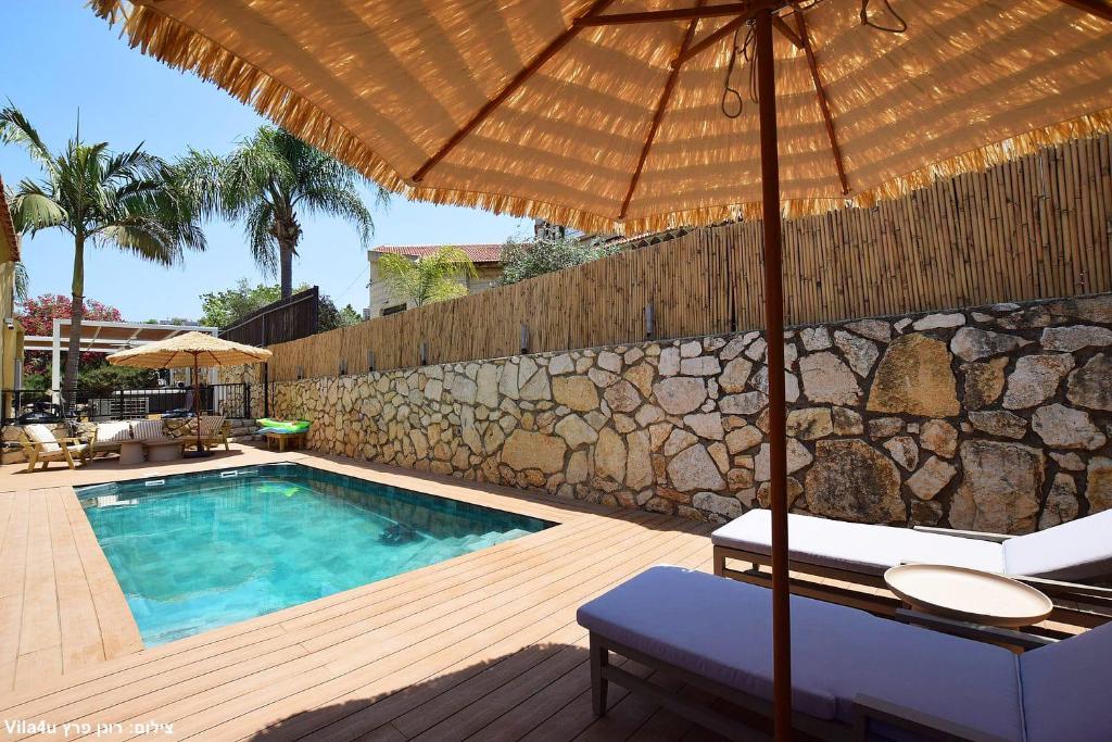 a pool with an umbrella and a chair and a table with an umbrella at וילה ארבל in Kefar Weradim