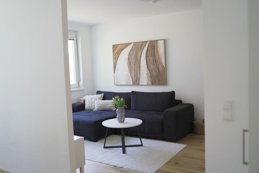 a living room with a blue couch and a table at Modernes Apartment in Schwechat in Schwechat