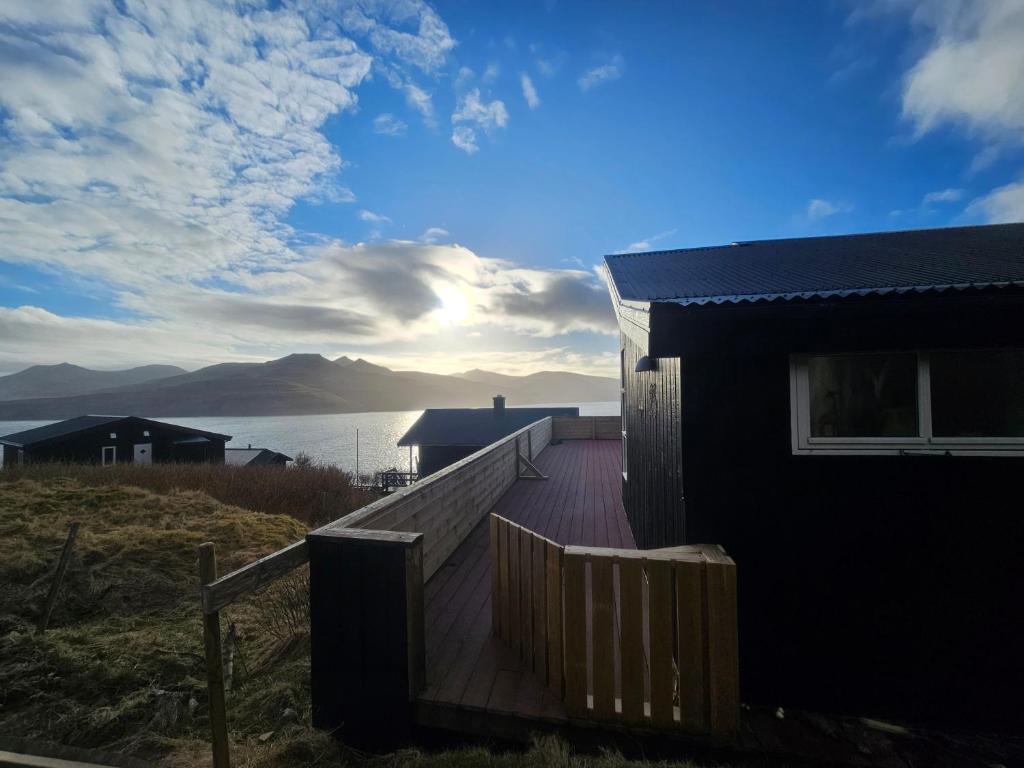 a house with a wooden deck next to the water at Mulheidar in Leynar