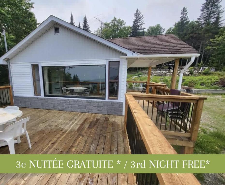a large deck with a patio and a house at Cozy Chalet with Breathtaking Mountain View in Notre-Dame-Des-Bois