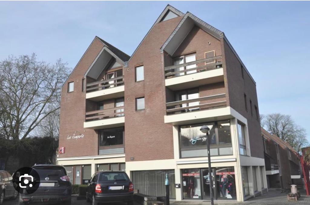 a tall brick building with cars parked in front of it at Les Remparts in Antoing