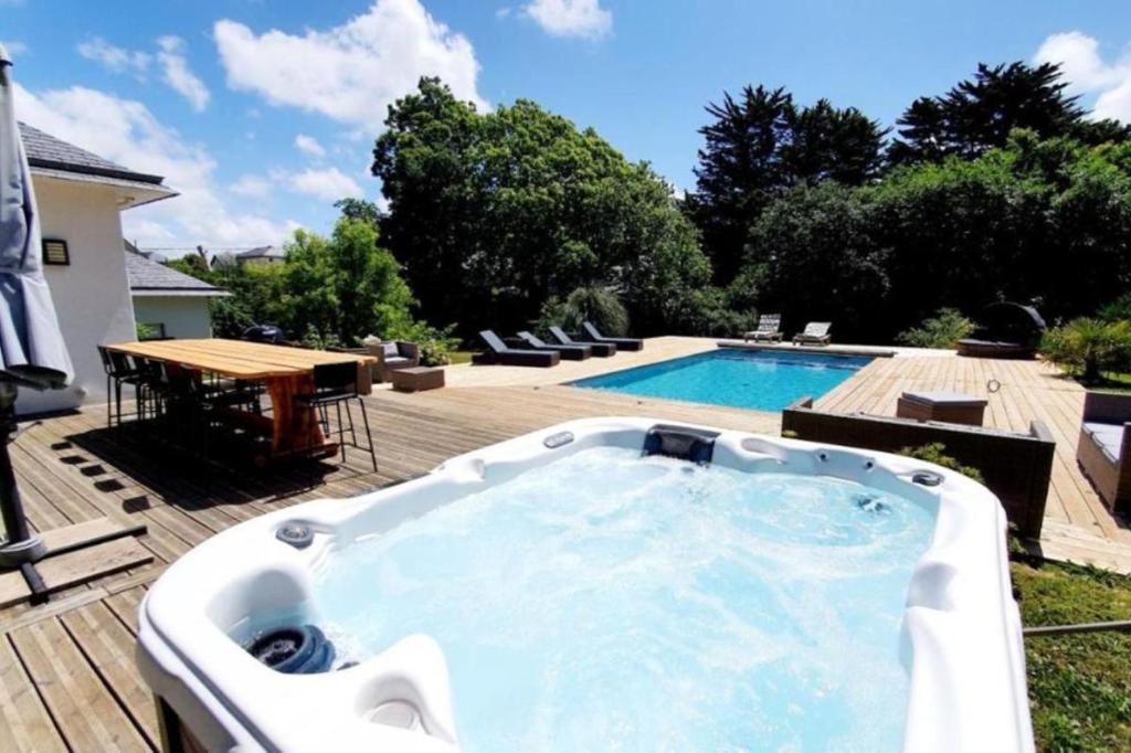 a hot tub on a deck next to a swimming pool at Villa des Abers vue mer, GR34, piscine chauffée in Landéda