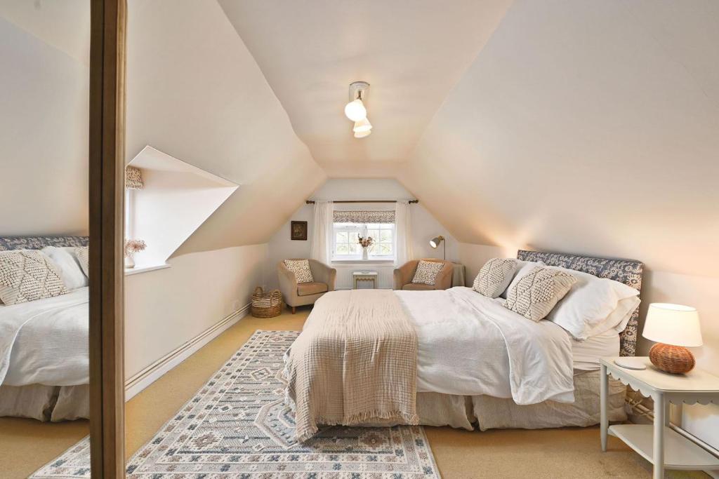 a attic bedroom with two beds and a window at Plum Pudding Stables by Bloom Stays in Faversham