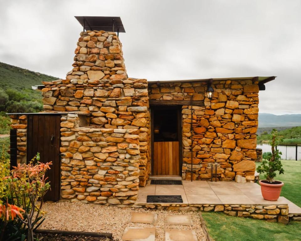 a stone building with a door in a yard at Uitkyk Kliphuisie in Uniondale